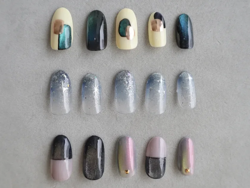 様々なネイルアートが施されたネイルチップが3列に並んでいます。抽象的・メタリックなデザイン、グリッターのグラデーション、ツートンや偏光カラーなど、多様なスタイルのネイルアートが紹介されています。