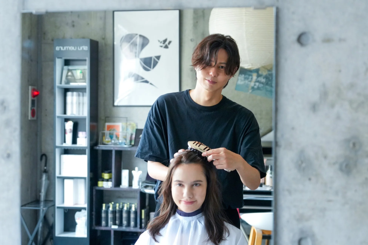 美容師が女性客の髪をスタイリング