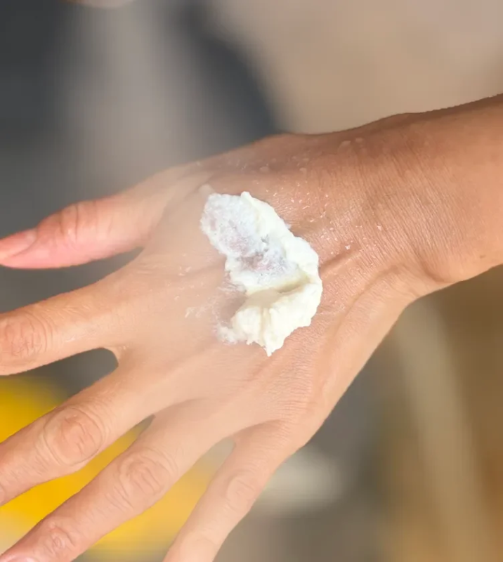 手の甲に白いクリーム状の物質が塗布されているクローズアップ画像です。スキンケア製品や美容液の試用、または保湿ケアの様子を表しているようです。