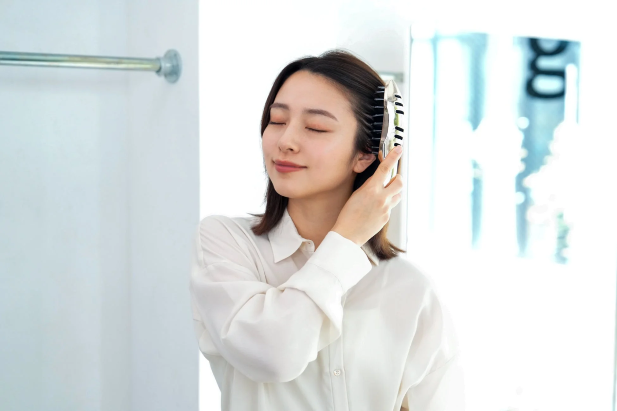 ヘアブラシで髪をとかす女性
