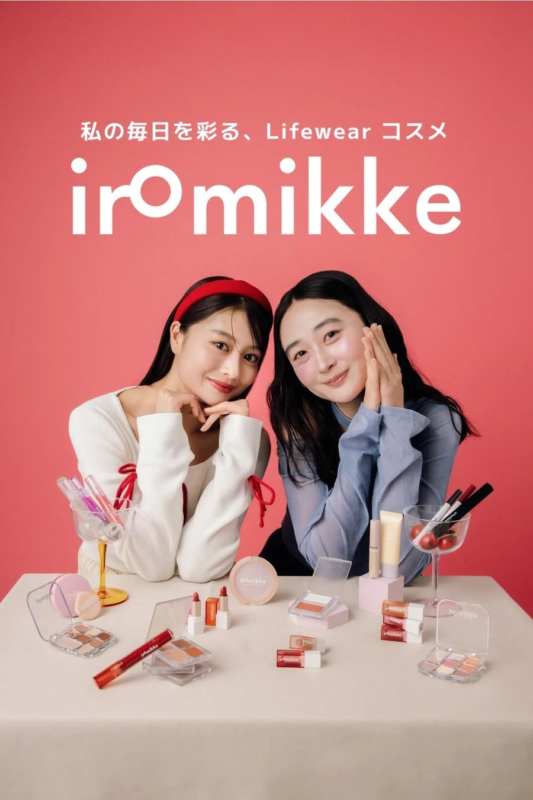 ピンクの背景の前で、笑顔の二人の女性が様々なコスメ製品に囲まれています。上部には「私の毎日を彩る、Lifewear コスメ iromikke」というキャッチコピーがあり、ブランド「iromikke」のプロモーションであることがわかります。
