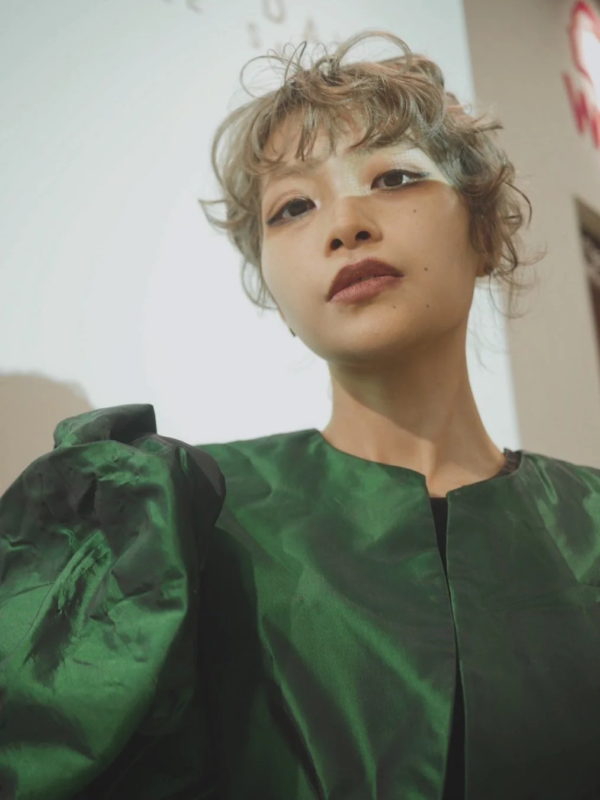 個性的なメイクとウェーブがかったショートヘアの女性