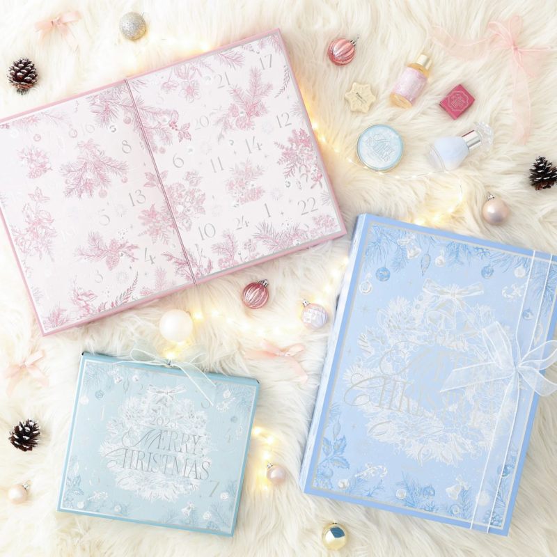 開かれたピンクのアドベントカレンダー、二つの青いギフトボックス、そしていくつかのコスメ製品