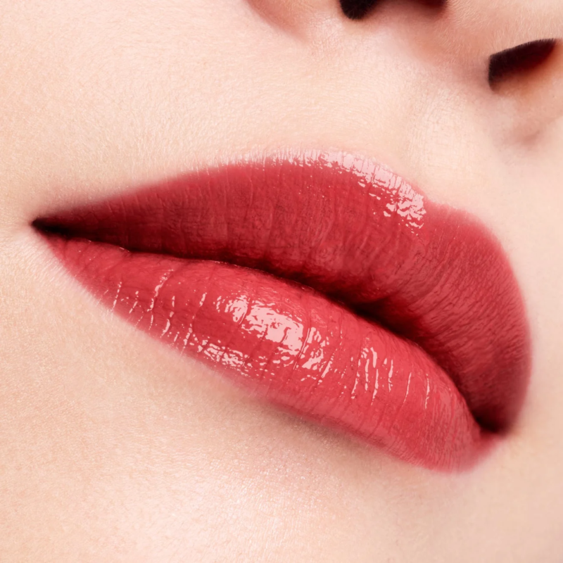光沢のある赤みがかったピンクのリップスティックを塗った唇