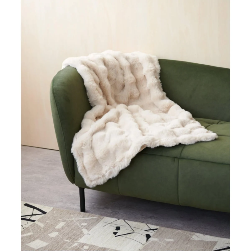 緑色のソファに、ふんわりとした白いフェイクファーのブランケット