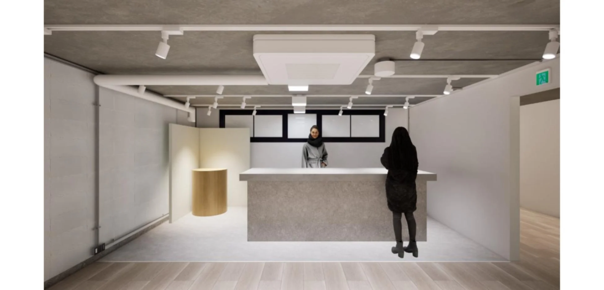 モダンでミニマリストな内装の空間で、受付カウンターの前に立つ2人の人物が描かれています。天井にはトラック照明と露出した配管があり、床はコンクリートと木材が組み合わされています。