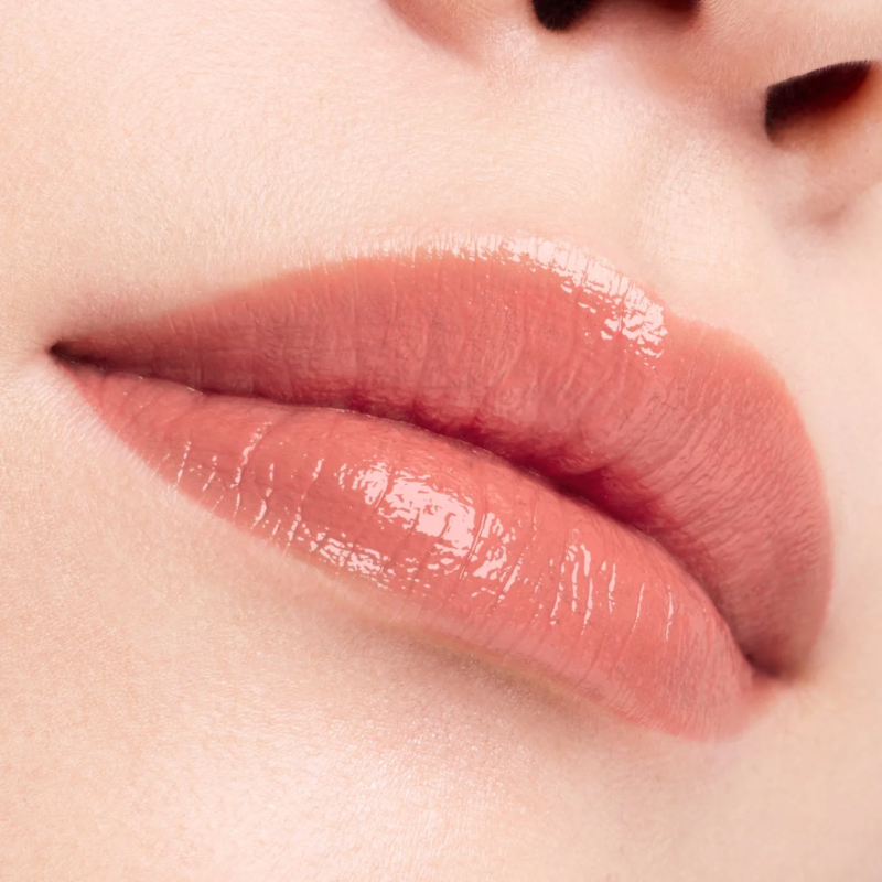 潤いのあるピーチ色のリップグロスを塗った唇