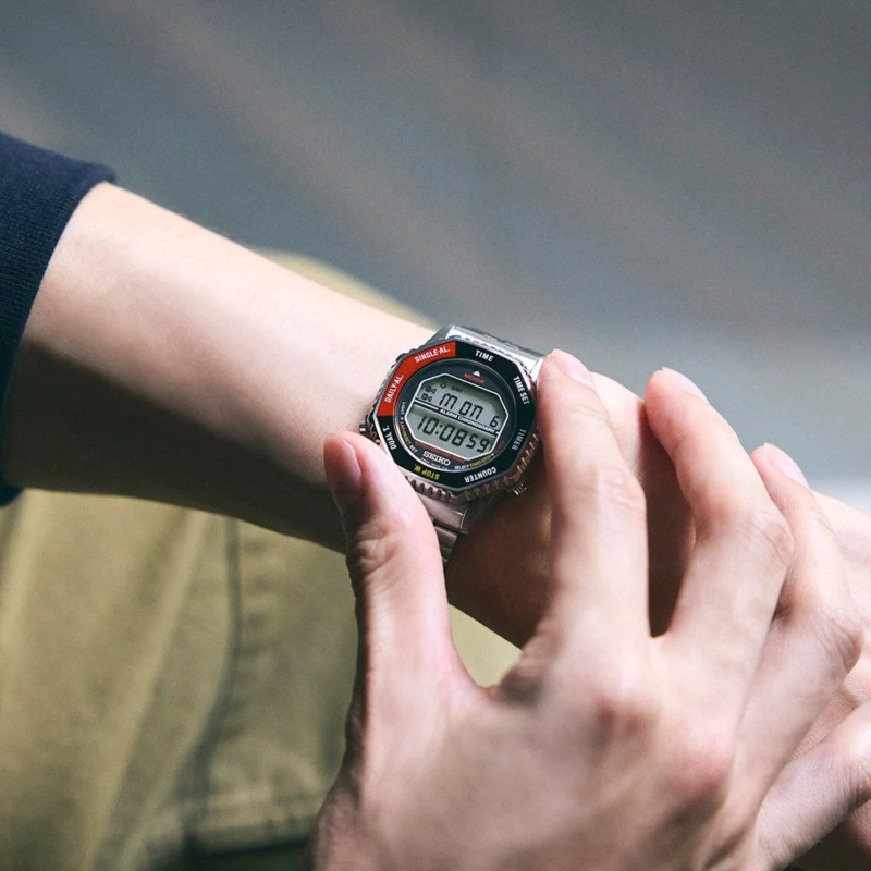 腕に装着されたセイコーのデジタル腕時計を、もう片方の手で操作している様子