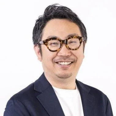 白背景の前で笑顔を見せる男性のポートレートです。