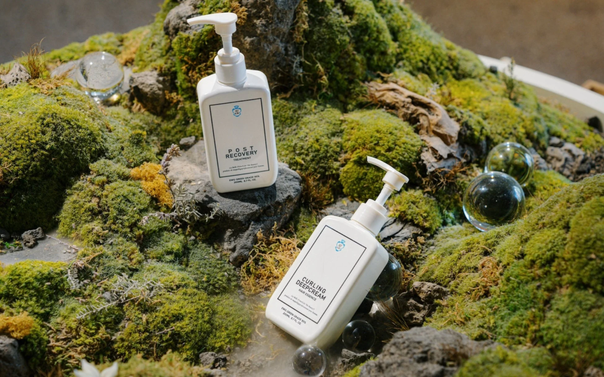苔むした岩場に置かれたヘアケア製品のボトル