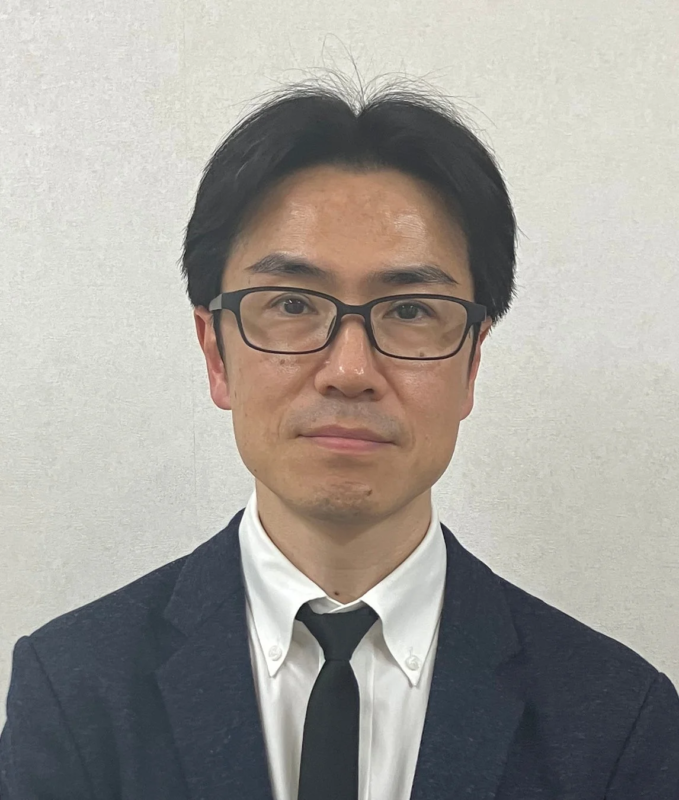 黒縁メガネをかけたアジア人男性のバストアップ写真です。