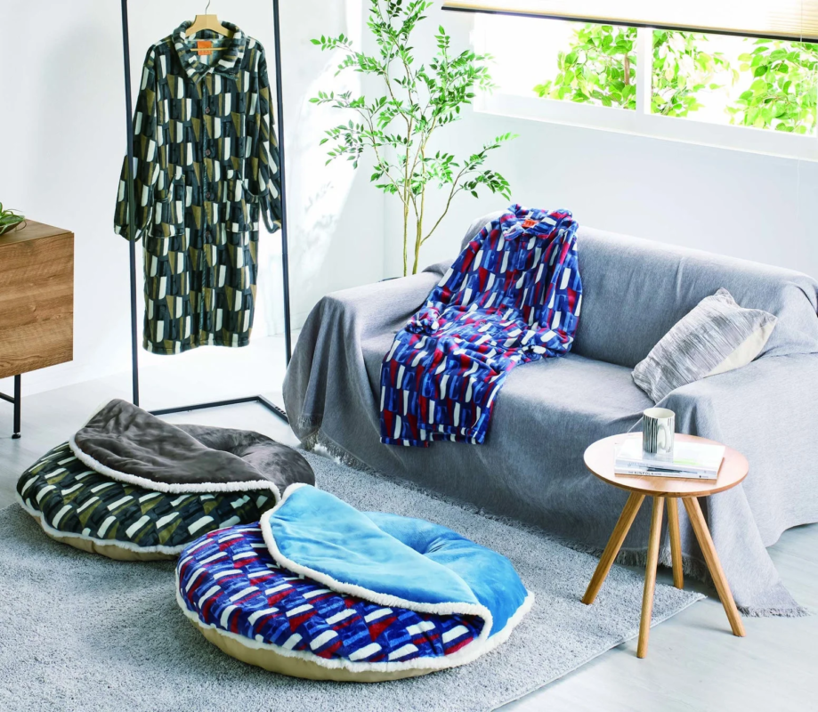 快適なリビングルームで、ソファにはブランケット、床には幾何学模様のペットベッド