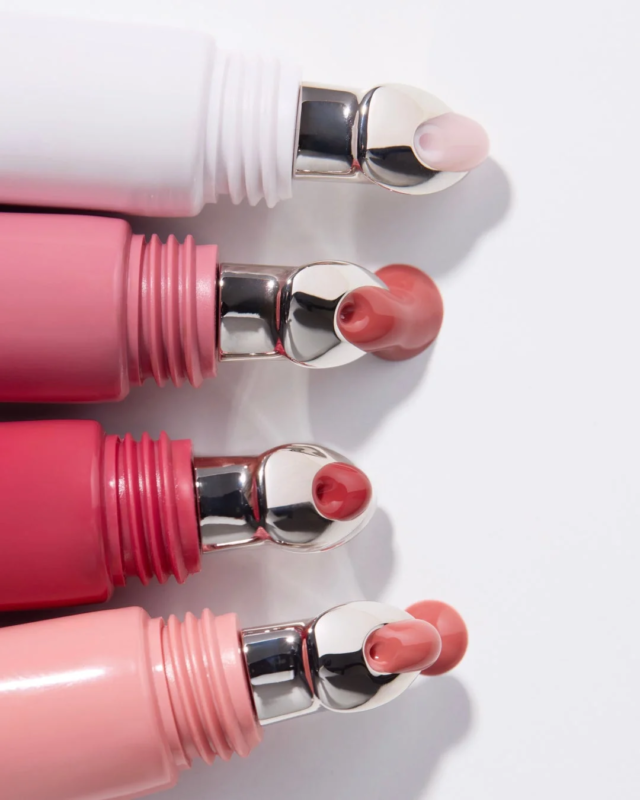 白い背景に、様々なピンクやヌードカラーのリップグロスが4本並べられています。