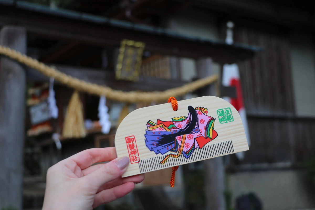 手に持たれた木製の櫛形のお守り