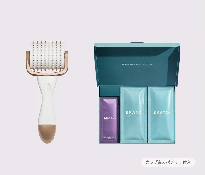 白いハンドルと金色のローラー部分を持つ美顔器と、EKATOブランドのスキンケア製品が入ったギフトボックスが写っています。ボックスには「TO THE BEST SKIN OF MY LIFE.」の文字があり、複数のパウチが含まれています。