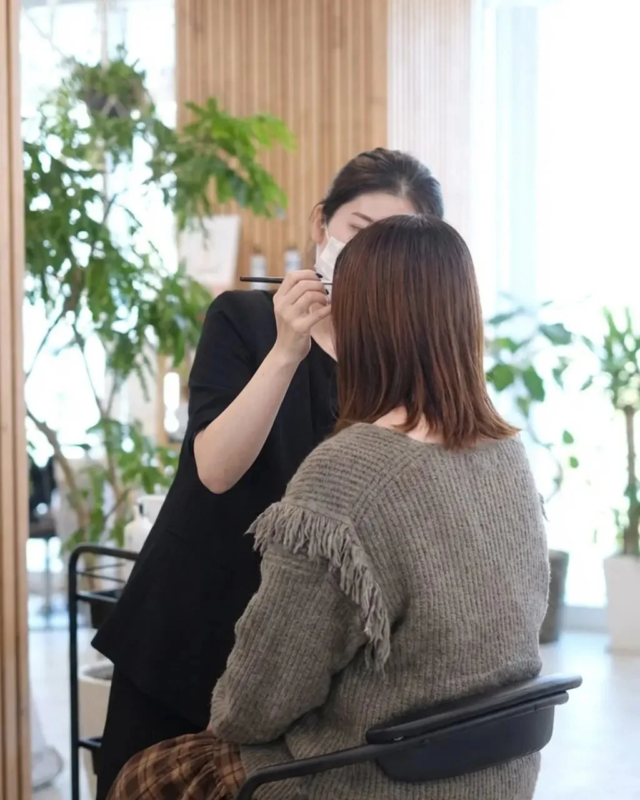 マスクを着用した美容師が女性客に施術を行っている様子