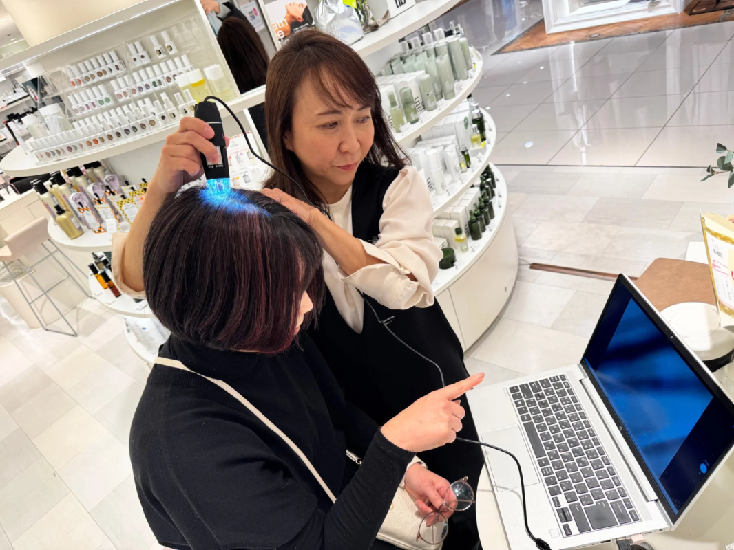 店舗で女性がスタッフから頭皮診断を受けている