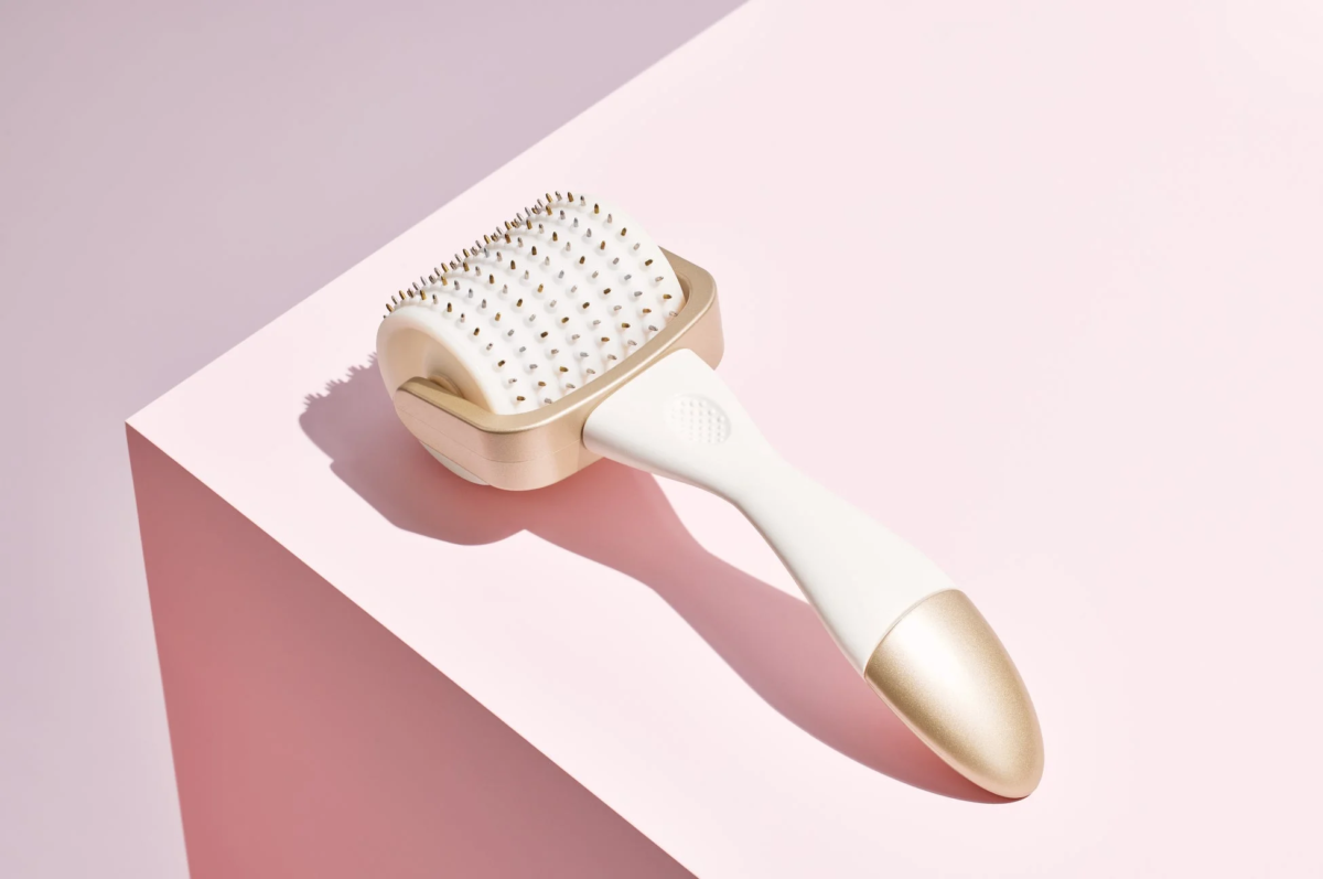 淡いピンクの背景に、白とゴールドのダーマローラーが置かれている画像です。ローラー部分には多数の細かい針が見え、モダンで清潔感のある美容機器の印象を与えます。