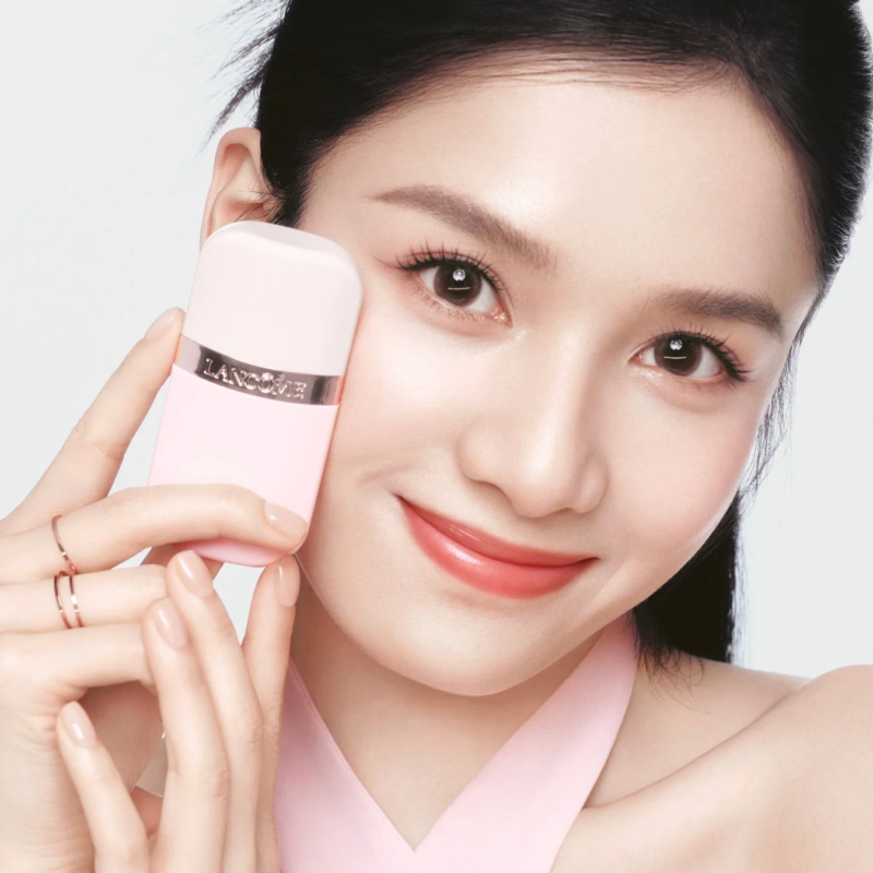 ピンクのランコム製品を顔の横に持つ若いアジア人女性