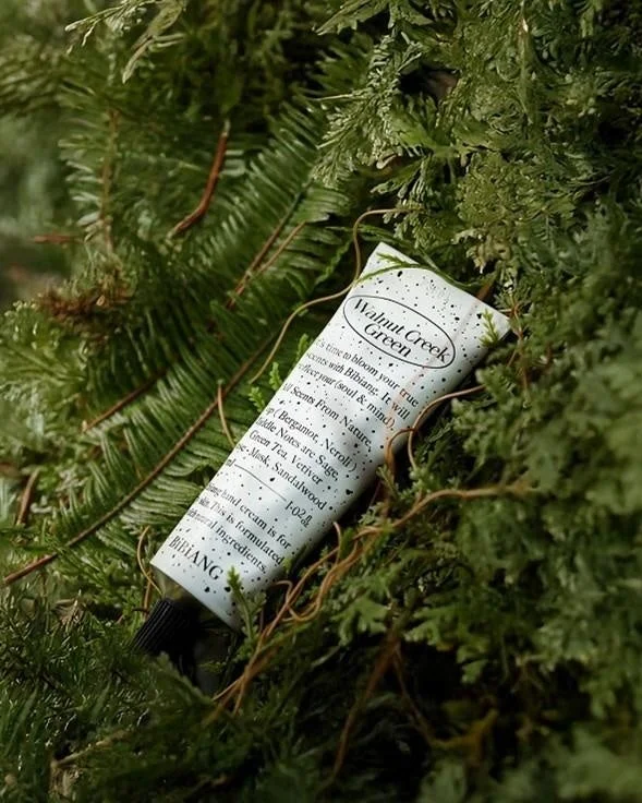 緑豊かな植物の中に置かれた、BIBIANG製ハンドクリームのチューブ