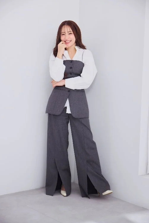 白いシャツとグレーのセットアップを着用し、明るいスタジオで笑顔を見せる大沢あかねさん