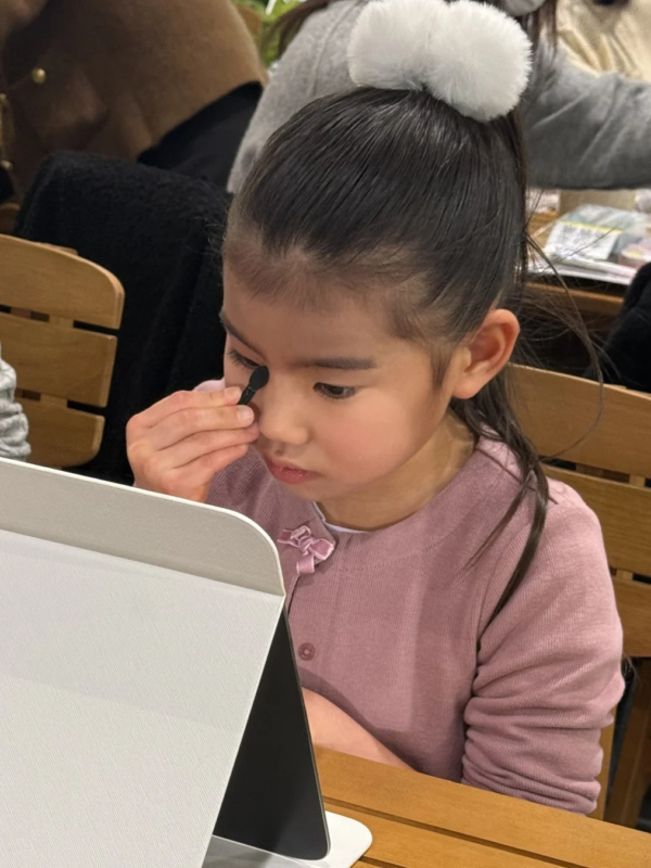 タブレットを鏡にメイクする子供