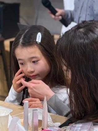 大人が子供にメイクを教える様子