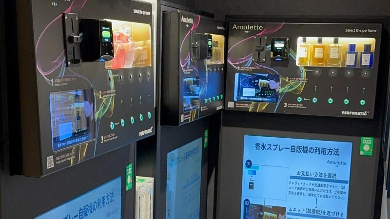 「PERFUMATIC Amulette」という香水スプレーの自動販売機が複数並んでいる様子です。支払い方法や香りの選び方、試香紙の使用方法などが日本語と英語で案内されており、利用者が香水を試したり購入したりできる体験型サービスを提供しています。
