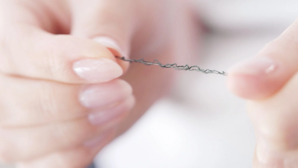 細い黒い糸を両端からつまむ指