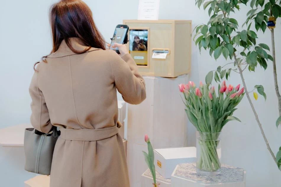 フォトブースをスマートフォンで撮影する女性