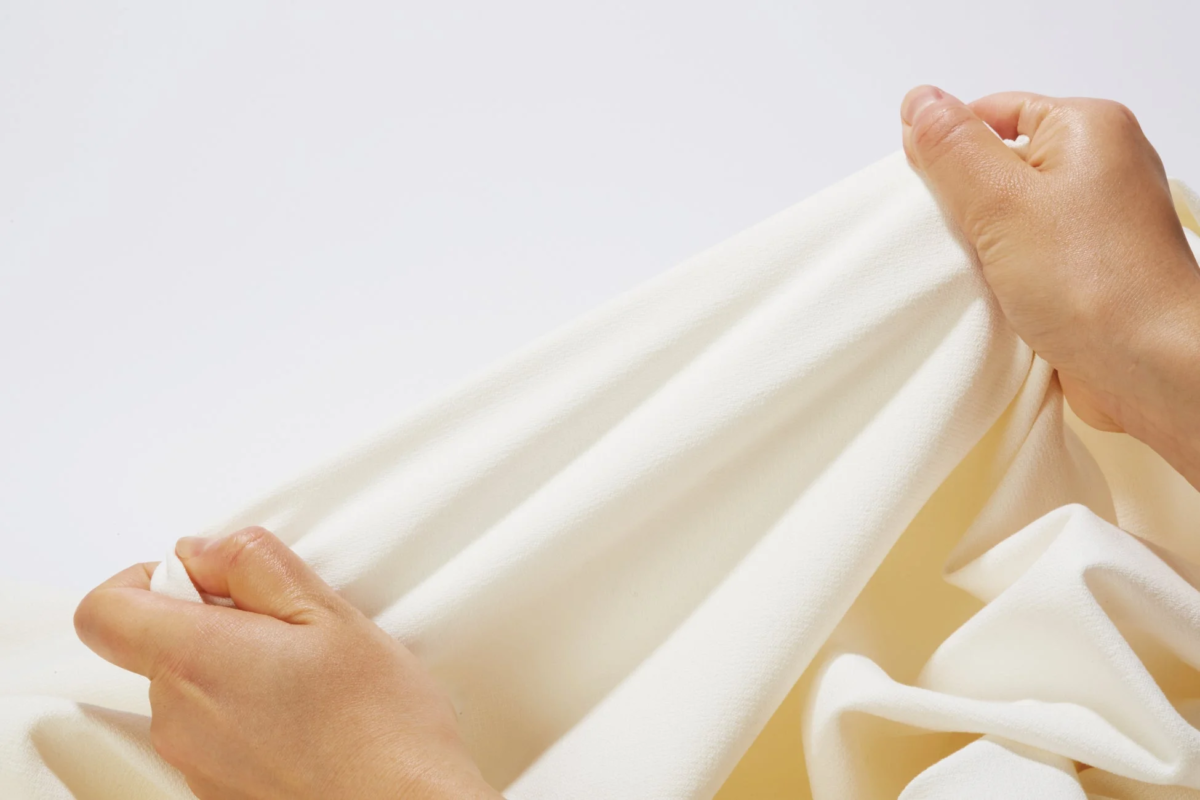 柔らかそうなオフホワイトの布を引っ張る手