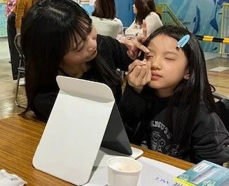 大人が子供にメイクを施す様子