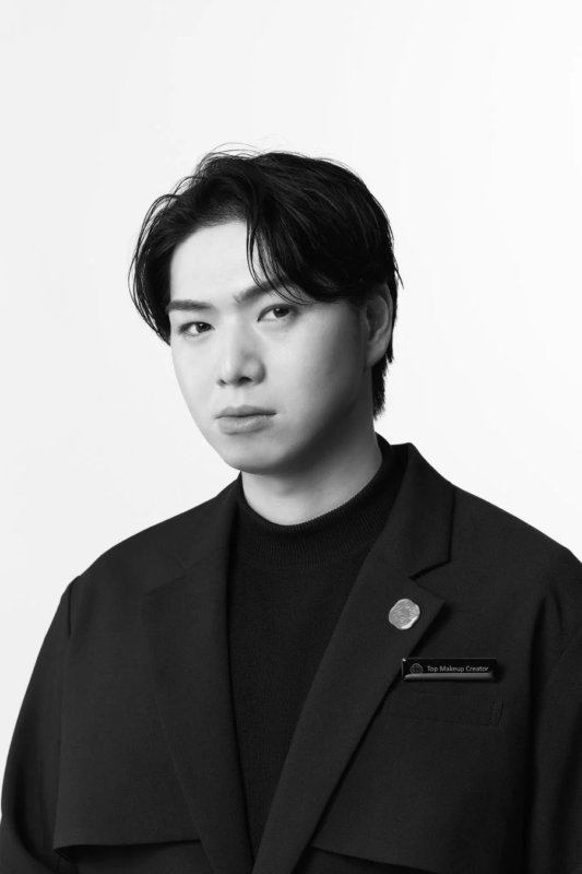 モノクロで撮影された、黒髪の若いアジア人男性のプロフェッショナルなポートレートです。