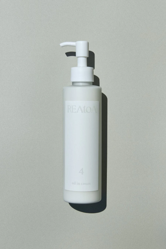 白いポンプ式のボトルに入った「REATOA」ブランドの「oil in cream」が、シンプルな背景に置かれています。