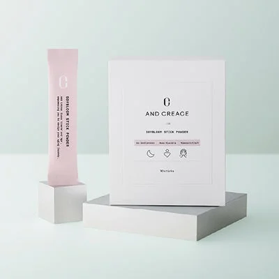 AND CREAGEのSOYBLOOM STICK POWDERが写っています。低分子コラーゲンペプチド、大豆イソフラボン、豚プラセンタ、ザクロエキスを配合した美容・健康補助食品で、30包入りの箱とスティック1本が白い台の上に置かれています。
