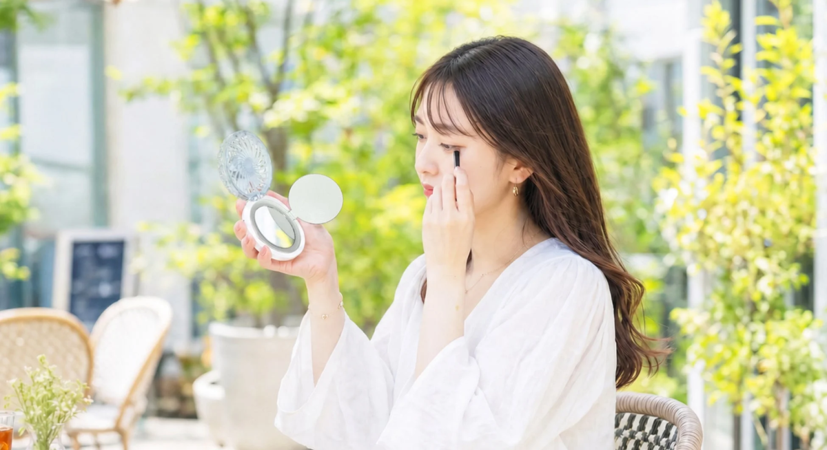 ミラーとリングライトでメイク直しをする女性