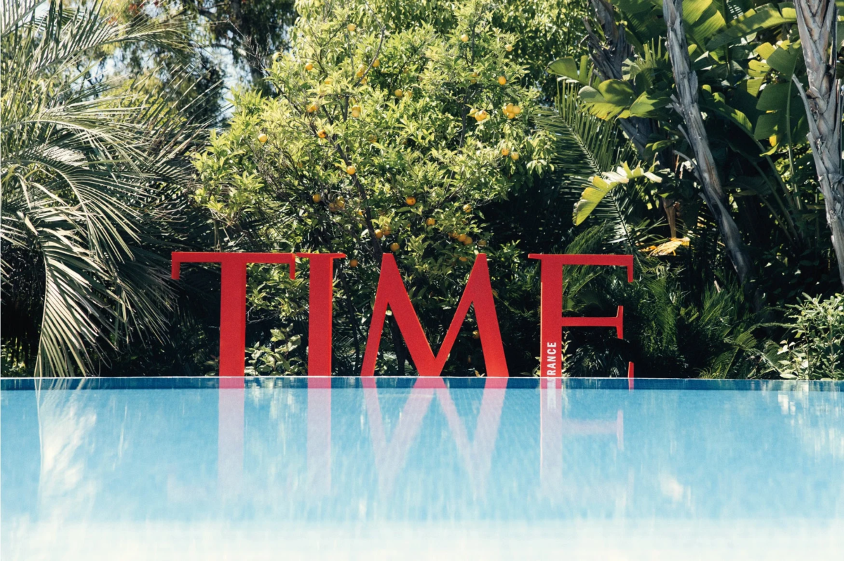 青いプールの向こうに、大きな赤い「TIME」の文字が立つ様子を捉えた画像