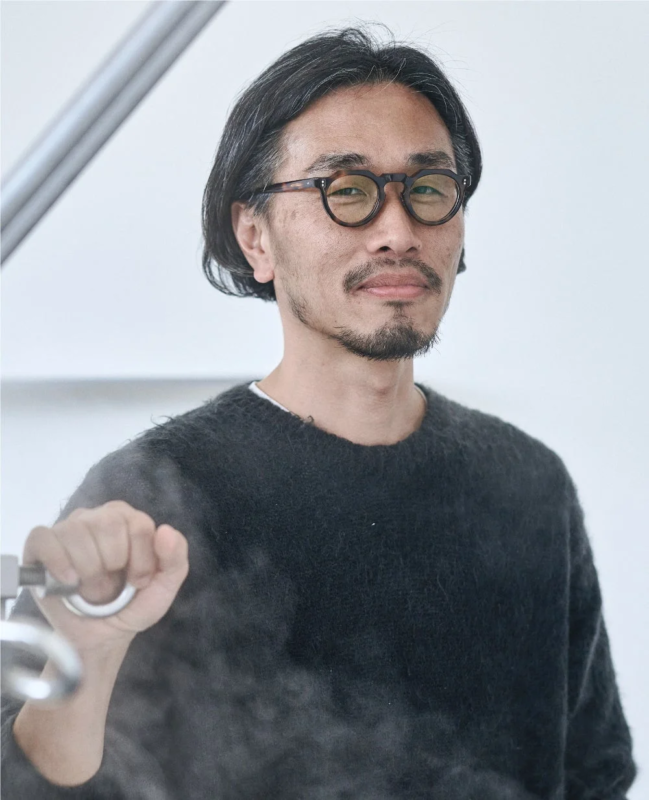 長髪と髭、丸眼鏡をかけたアジア系の男性のポートレート