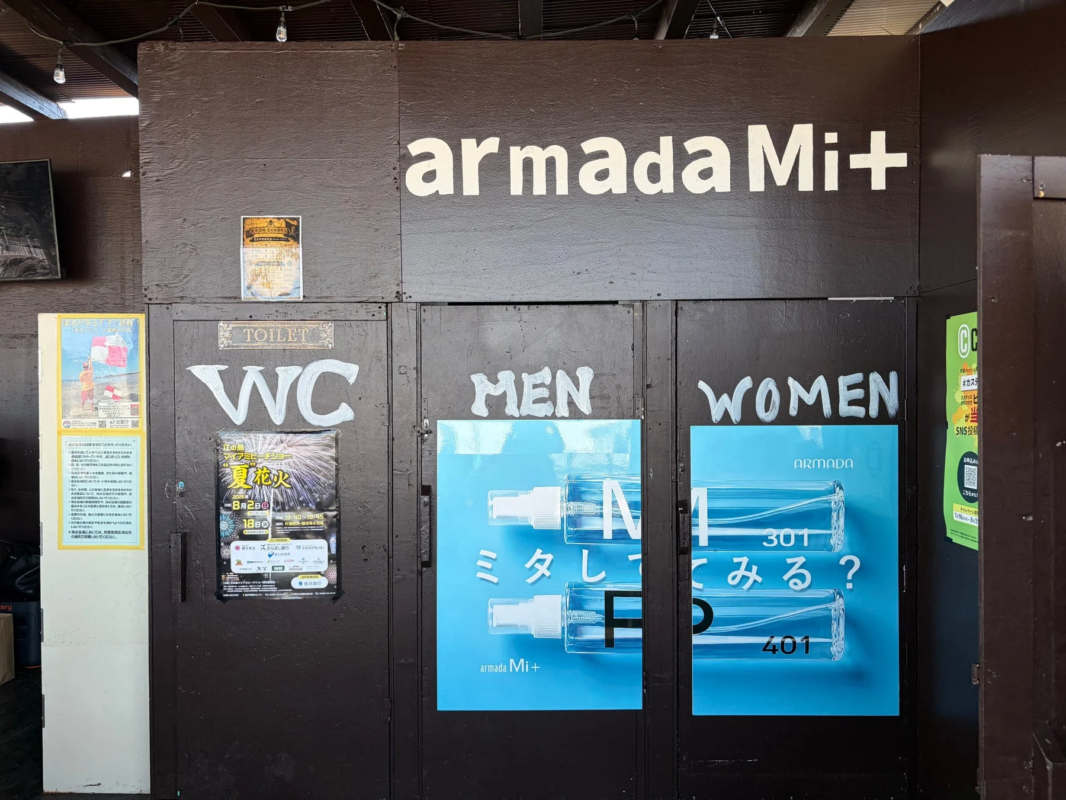 armada Mi+のロゴと製品広告が貼られたトイレの入り口