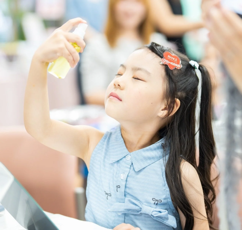 顔にミストスプレーをかける少女