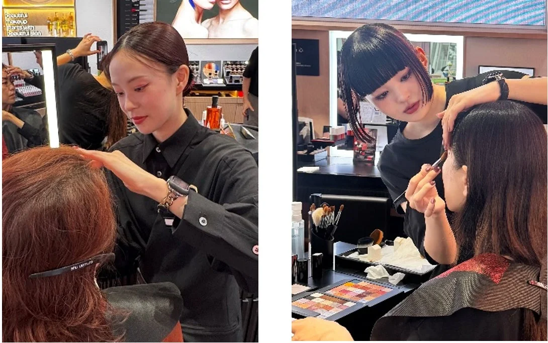 美容カウンターで、2人のメイクアップアーティストが女性客にメイクを施している場面