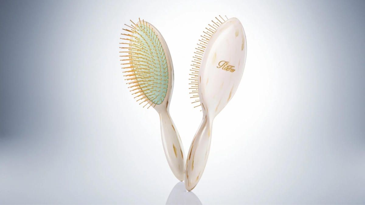金色のピンとマーブル模様の白い持ち手を持つRefaのヘアブラシ2本が向かい合うように配置されている