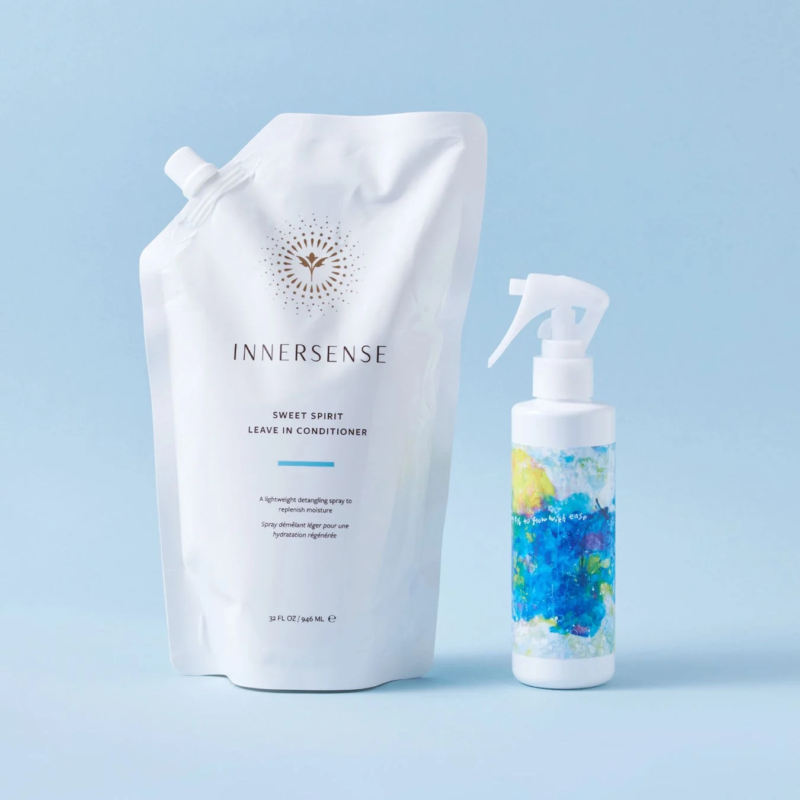 INNERSENSEのSWEET SPIRITリーブインコンディショナーの詰め替え用パウチとスプレーボトルが、水色の背景に置かれています。パウチには製品名と説明が記載されており、ボトルはカラフルなデザインです。ヘアケア製品を紹介する清潔感のある画像です。