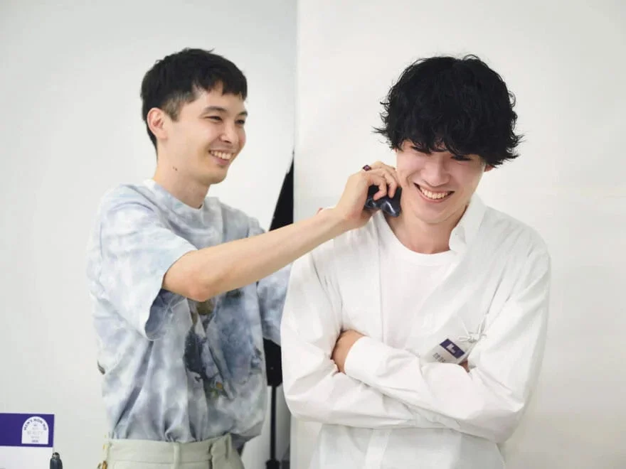 笑顔の男性二人が写っています。一人がもう一人の肩に手を置き、楽しそうに交流している様子で、リラックスした和やかな雰囲気が伝わってきます。