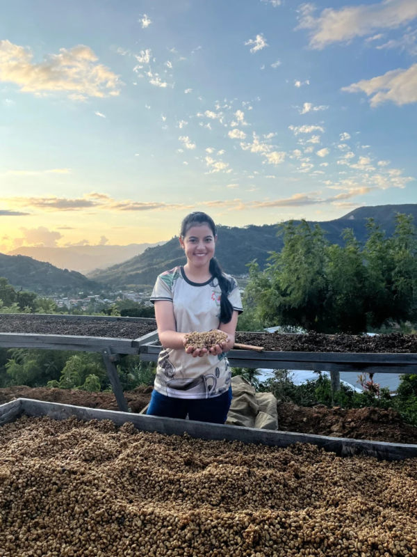 夕焼けを背景にコーヒー豆を抱える女性