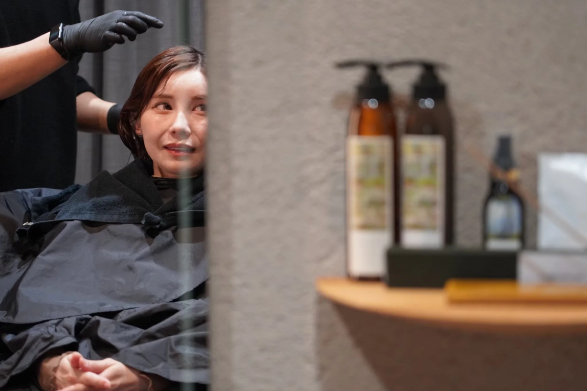 美容院で女性がヘアトリートメントを受けている様子
