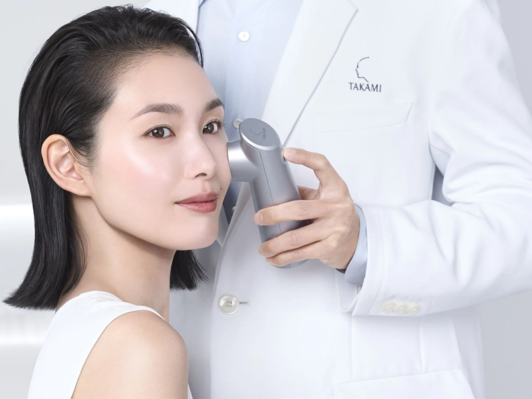 白い清潔感のある空間で、女性が美容機器を使ったフェイシャルケアを受けている様子