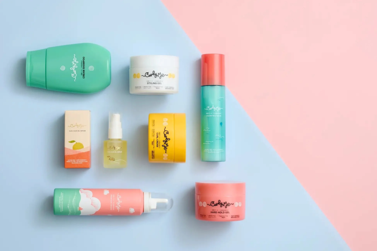 パステルカラーの背景に、天然パーマやくせ毛用のヘアケア製品(シャンプー、スタイリングジェル、ヘアオイルなど)が複数並べられた商品写真