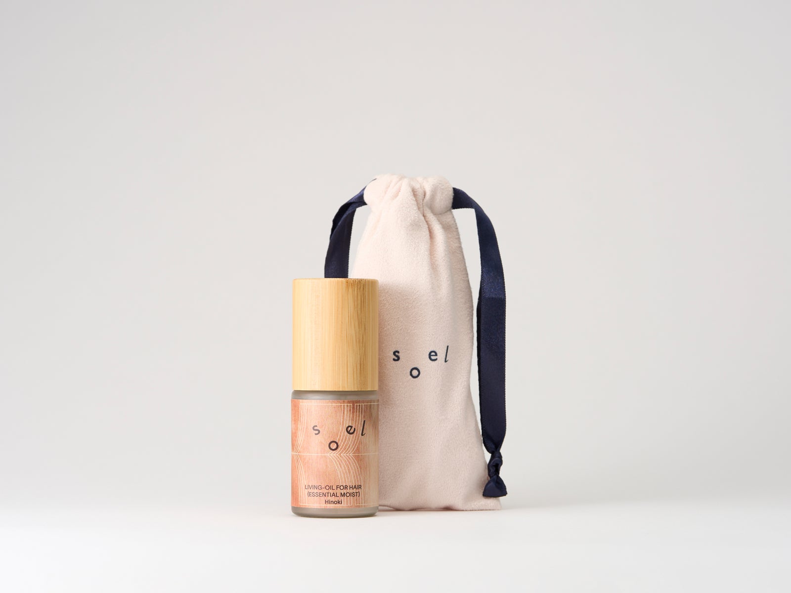 木のキャップのボトルに入ったsoelのヘアオイルと、紺のリボンがついた生成りの巾着袋