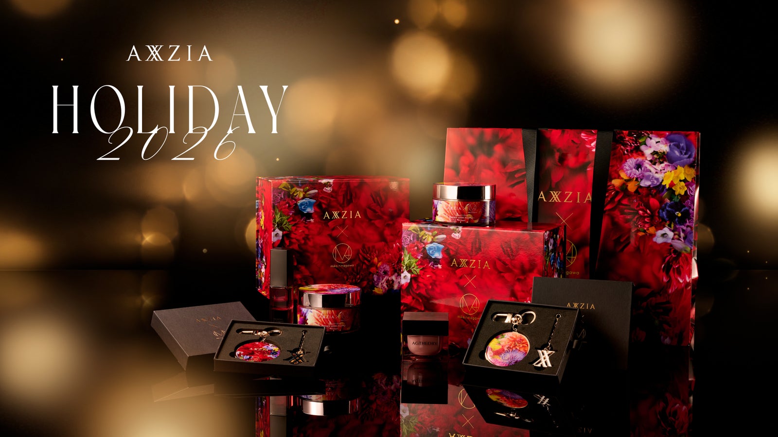 黒と金のボケを背景に、赤い花柄のギフトボックスやショッパーを並べたAXXZIA HOLIDAY 2026のビジュアル